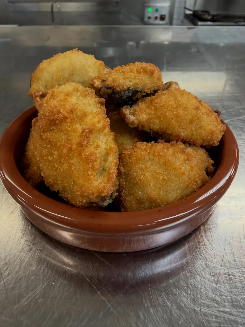 Fried croquettes in their shells, in a terracotta dish