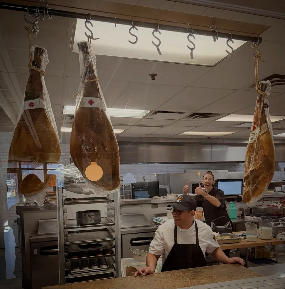 Cured hams hanging over the kitchen, seen through the pass