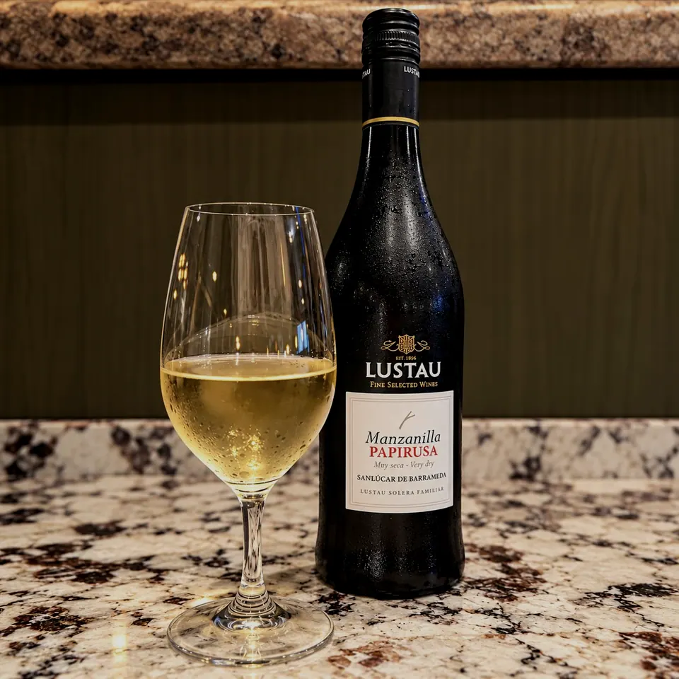 A glass of pale sherry beside a bottle of Lustau Manzanilla Papirusa