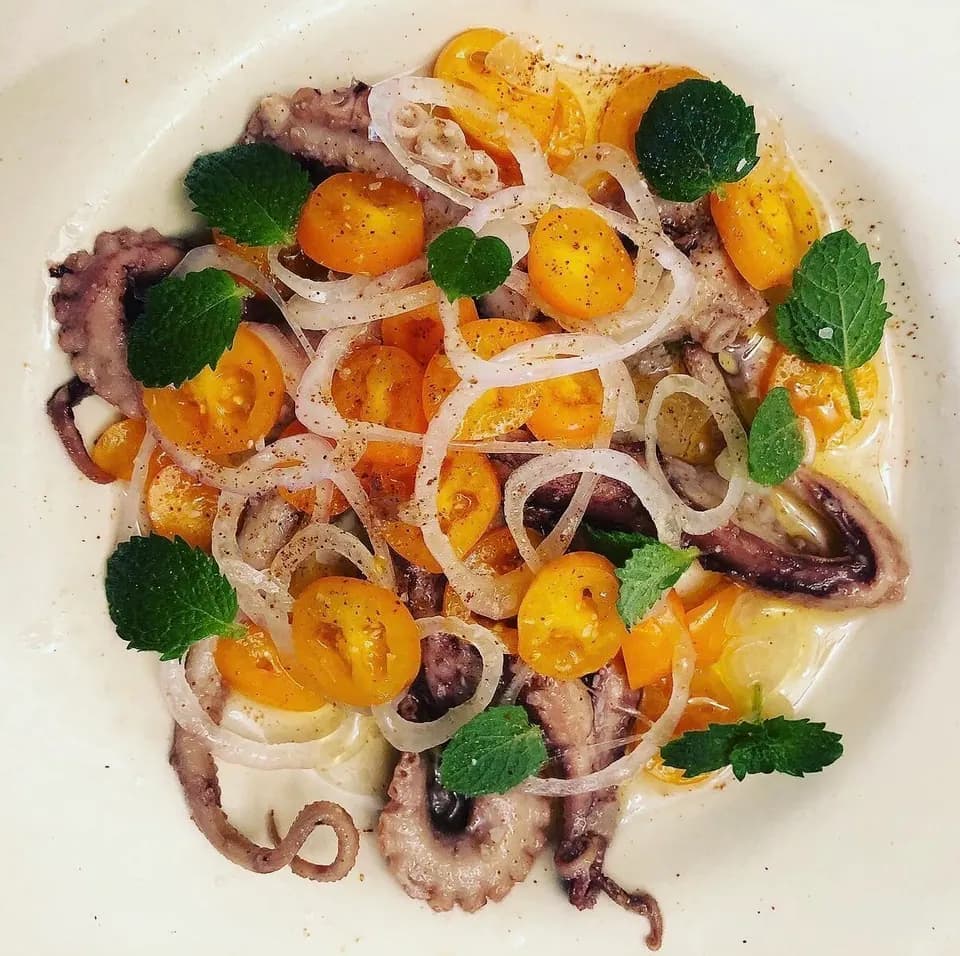 Octopus with yellow cherry tomatoes, sliced onion and mint